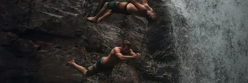Groupe en canyoning sautant dans une cascade
