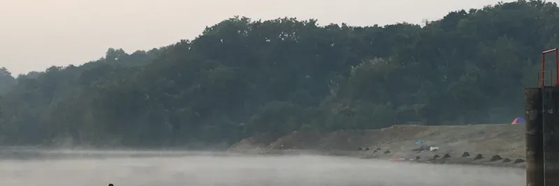 Lac calme dans la brume matinale avec un bateau de pêche