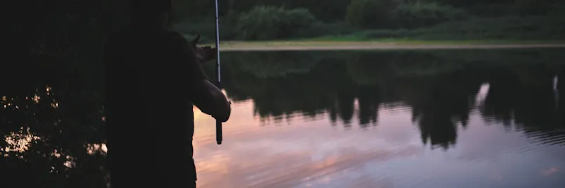 Canne à pêche au bord de la rivière au coucher du soleil
