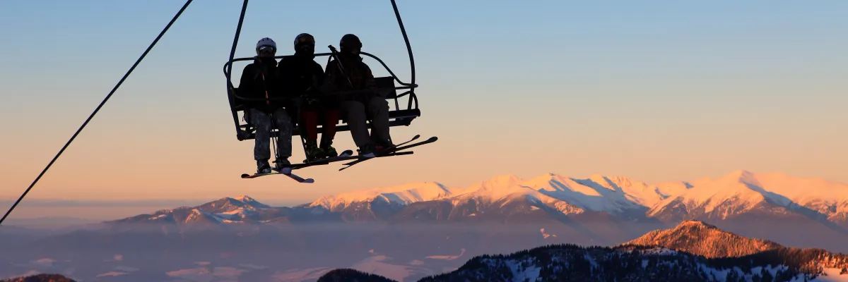Télésiège avec skieurs sous un ciel de fin de journée
