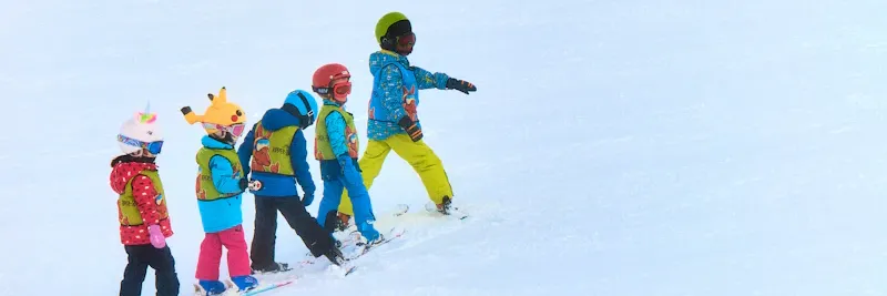 Moniteur de ski avec un groupe d'enfants sur la piste