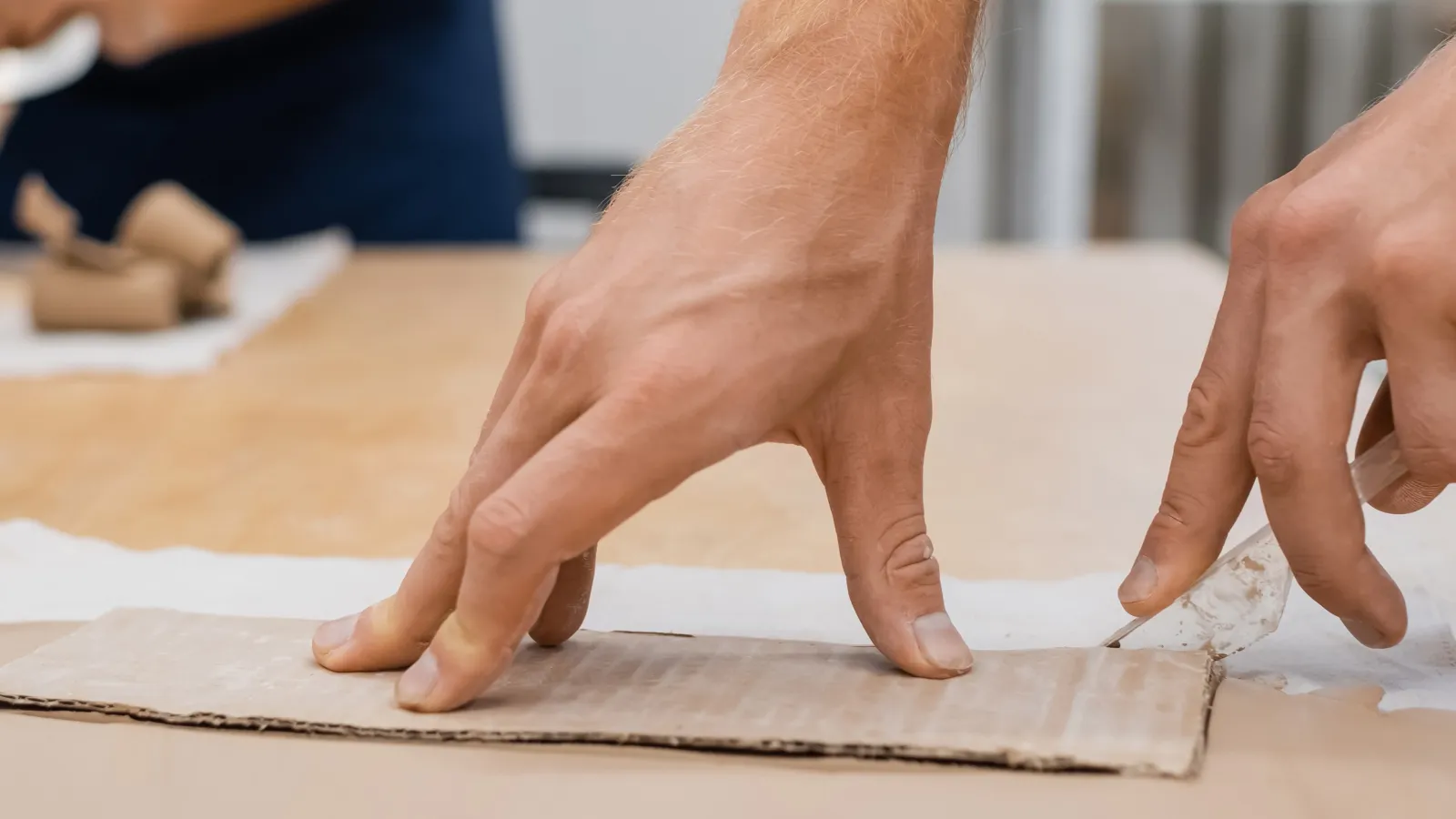 Artisan découpant de l'argile au couteau dans un atelier de poterie