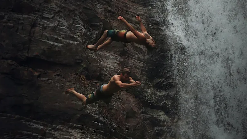 Groupe en canyoning sautant dans une cascade