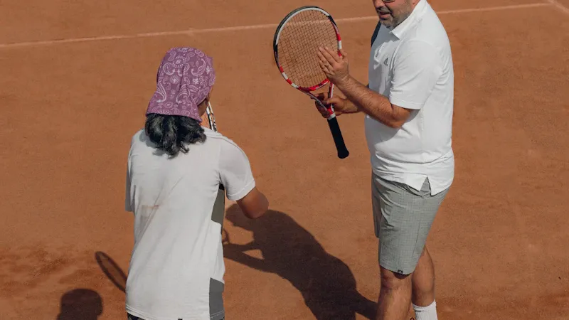 Coach de tennis serrant la main d'un élève au filet