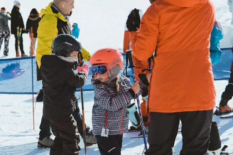 Moniteur ajustant les skis d'un enfant