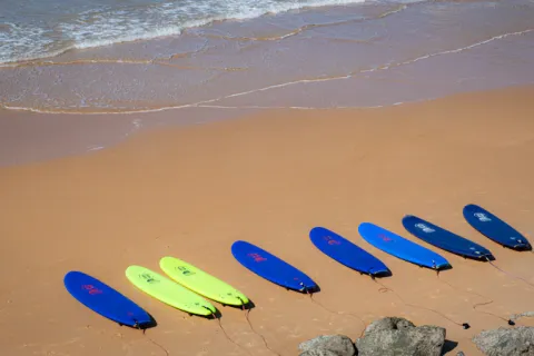 Rangée de planches de surf colorées sur le sable
