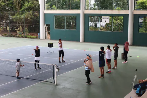 Groupe d'enfants en école de tennis avec moniteur