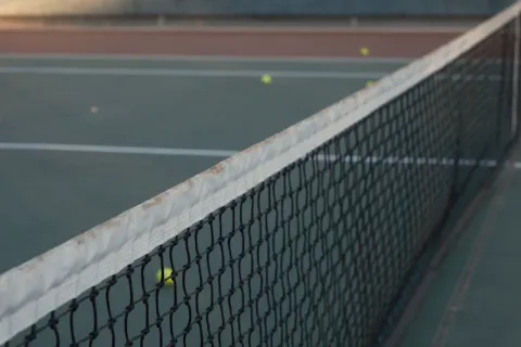 Raquettes et balles posées sur le filet d'un court