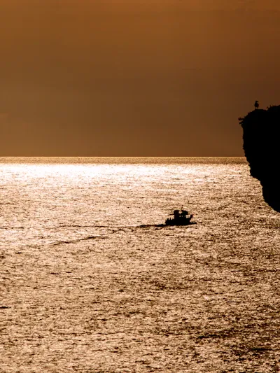 Groupe en kayak de mer longeant des falaises au coucher du soleil