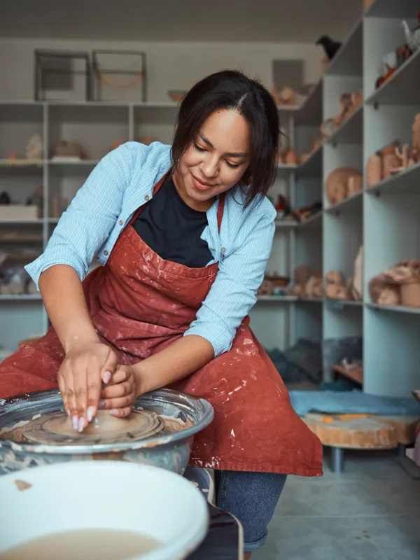 Jeune femme façonnant un pot sur un tour de poterie