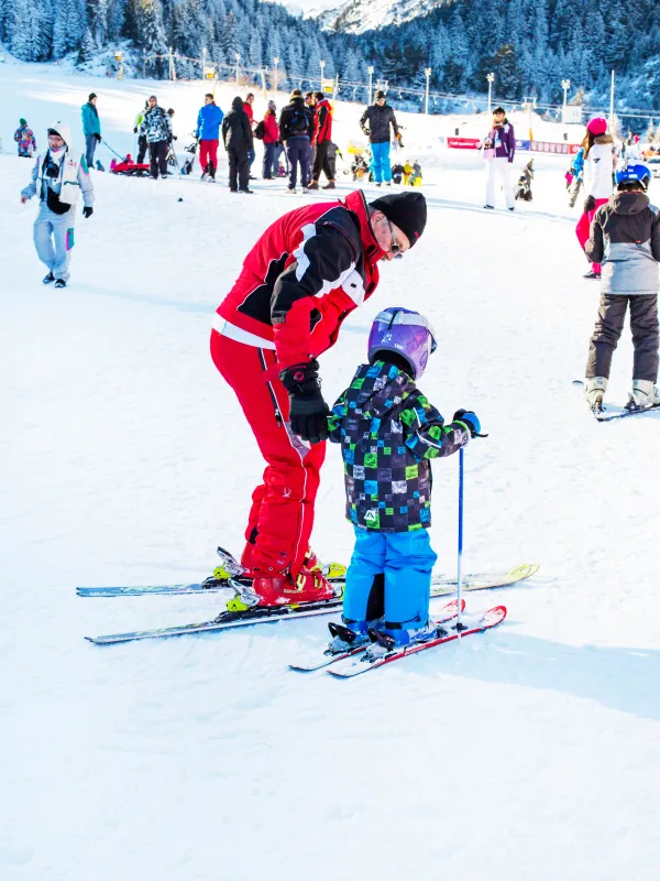 Moniteur et enfant apprenant à skier sur la piste