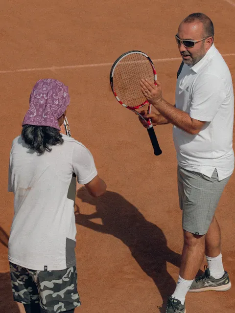 Coach enseignant à un élève sur court en terre battue
