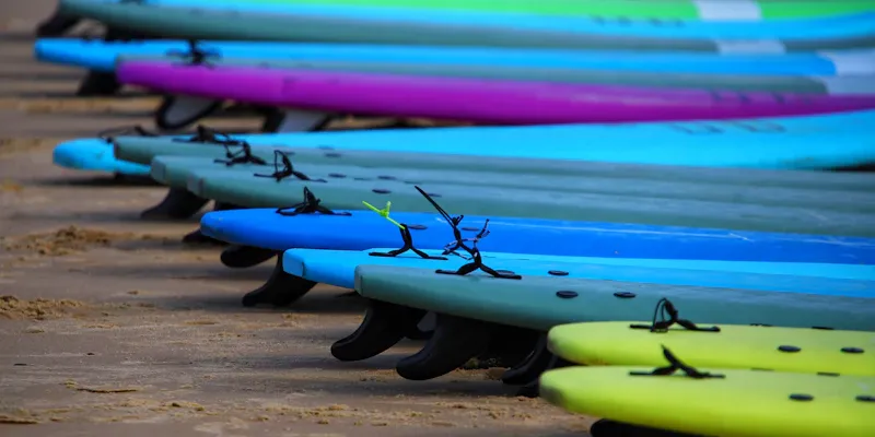 Rangée de kayaks et paddles colorés sur le sable, prêts pour la location