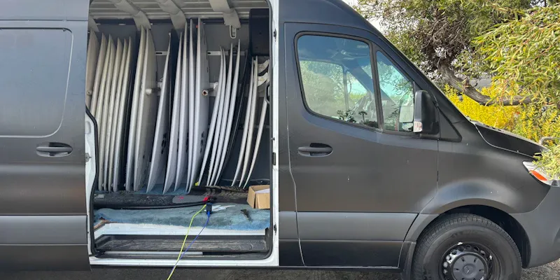 Guide préparant le matériel — combinaisons, casques, baudriers — devant son camion