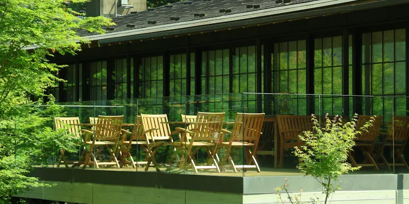 Vue du club-house avec terrasse donnant sur les courts, joueurs en arrière-plan