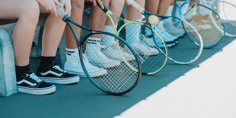 Panier de balles et raquettes posées sur un banc au bord du court