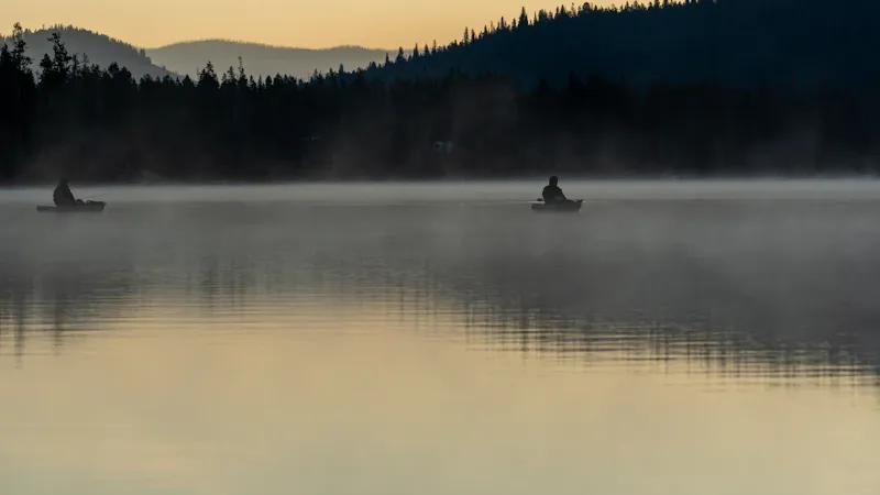 Pêcheur lançant sa ligne au lever du soleil sur un lac