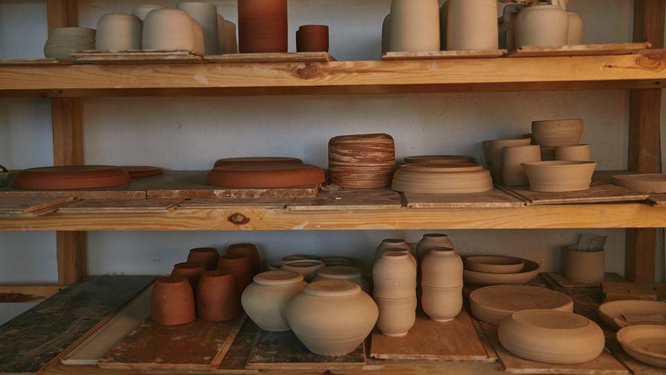 Bols en céramique sur étagères en bois dans un atelier de poterie