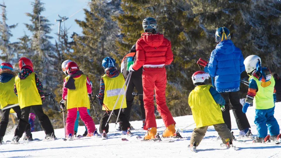 Moniteur de ski enseignant à un groupe d'enfants